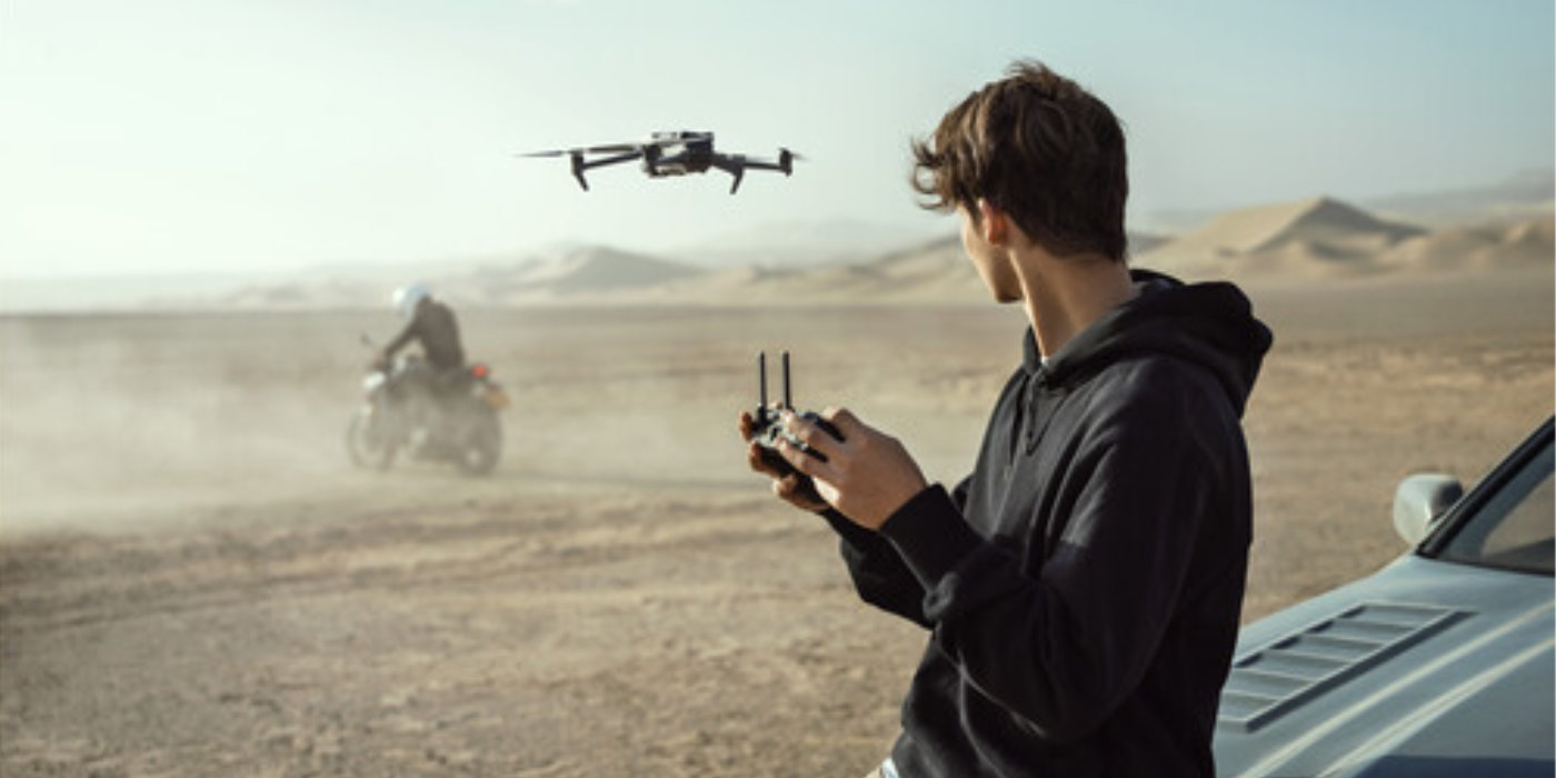 An image showing the DJI Mavic 3 being piloted by a young man in a desert.
