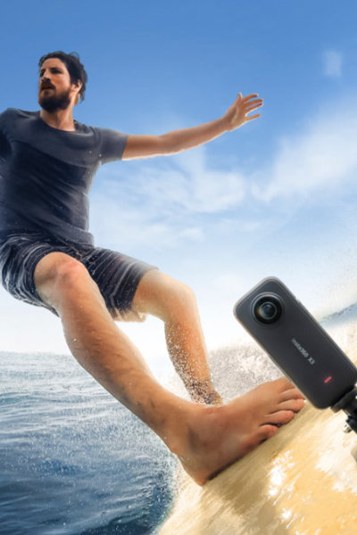 The Insta360 X3 Waterproof Action Camera attached to a surfboard with a man surfing.