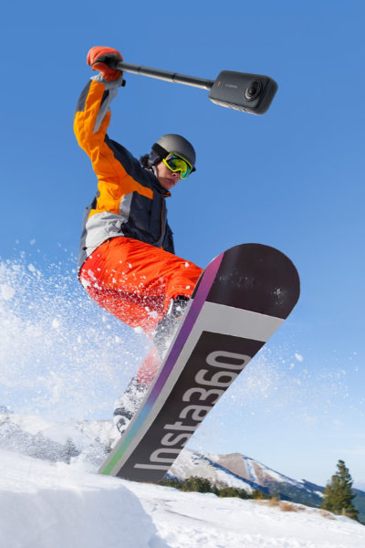 The Insta360 X3 Waterproof Action Camera attached to a selfie-stick as a person snowboards.